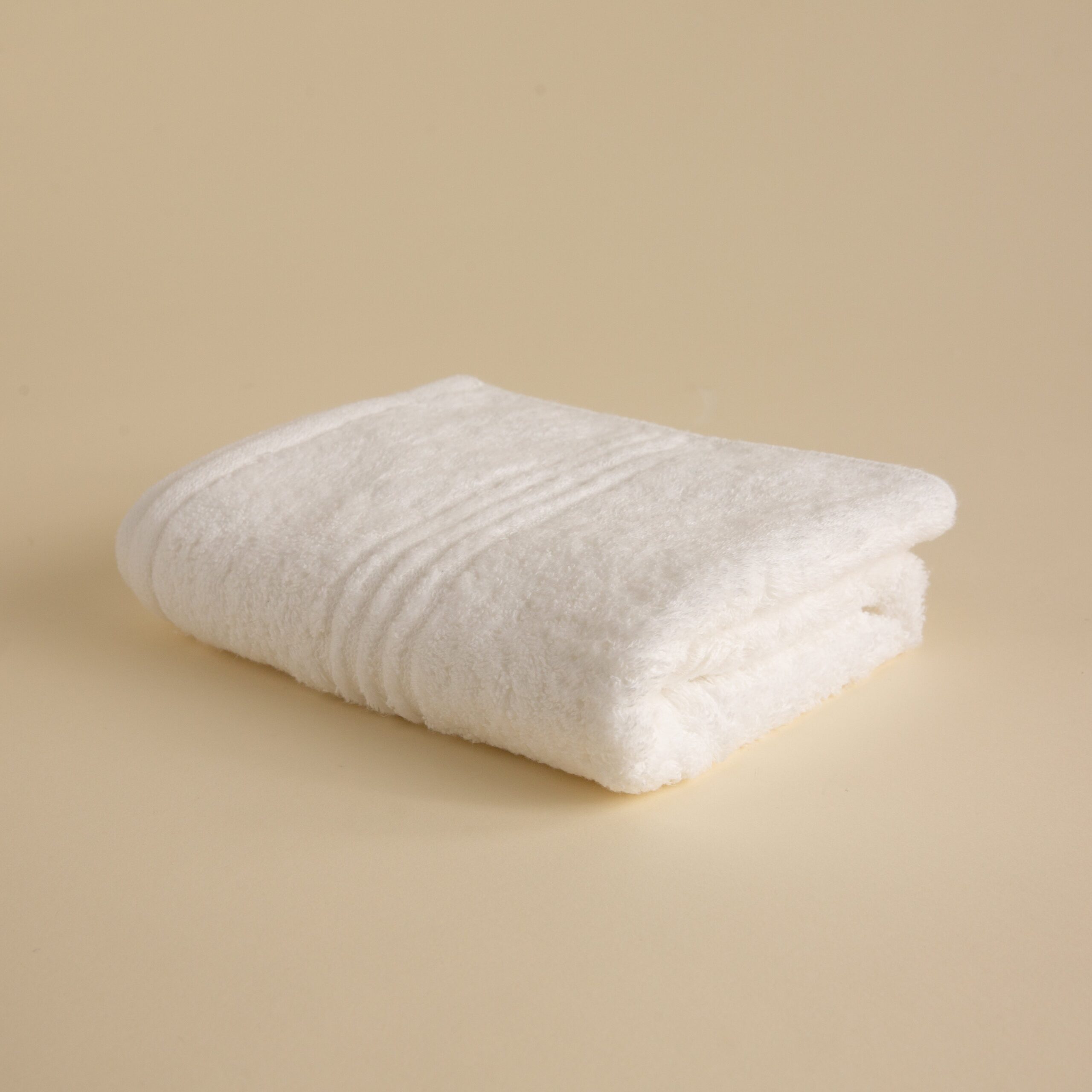 FineDetailsDay1-411 Stack of white towels in various sizes on a beige background