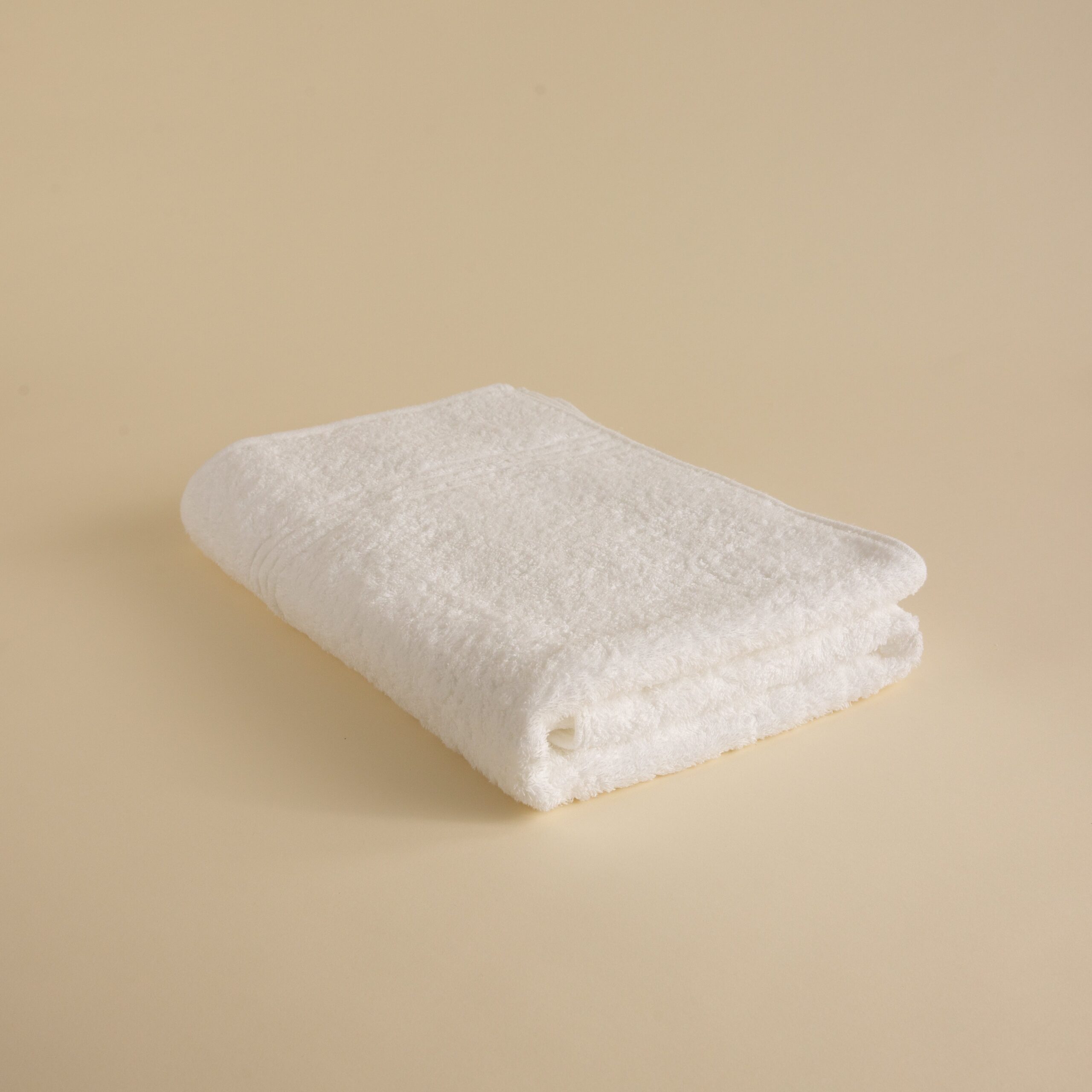 FineDetailsDay1-438 Stack of white towels in various sizes on a beige background