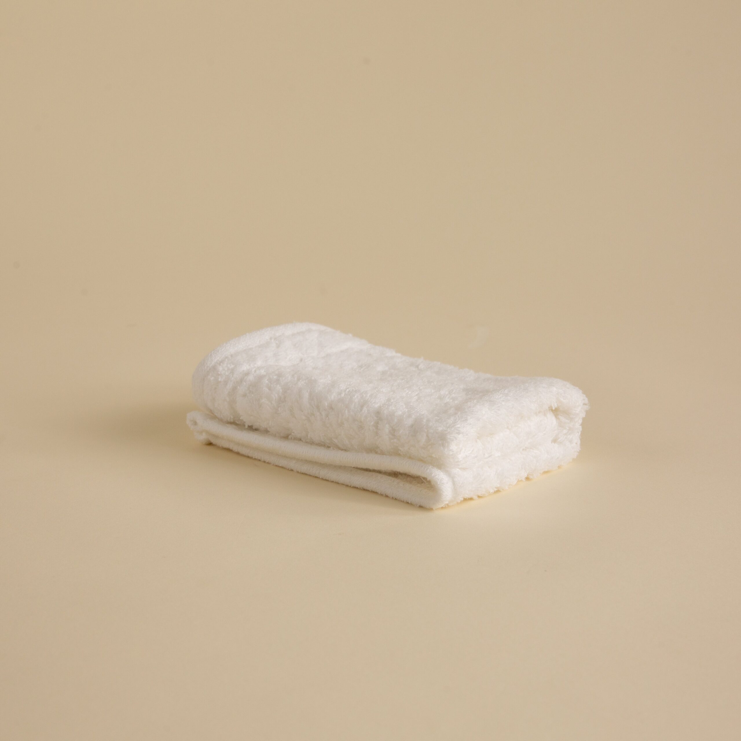 FineDetailsDay1-439 Stack of white towels in various sizes on a beige background