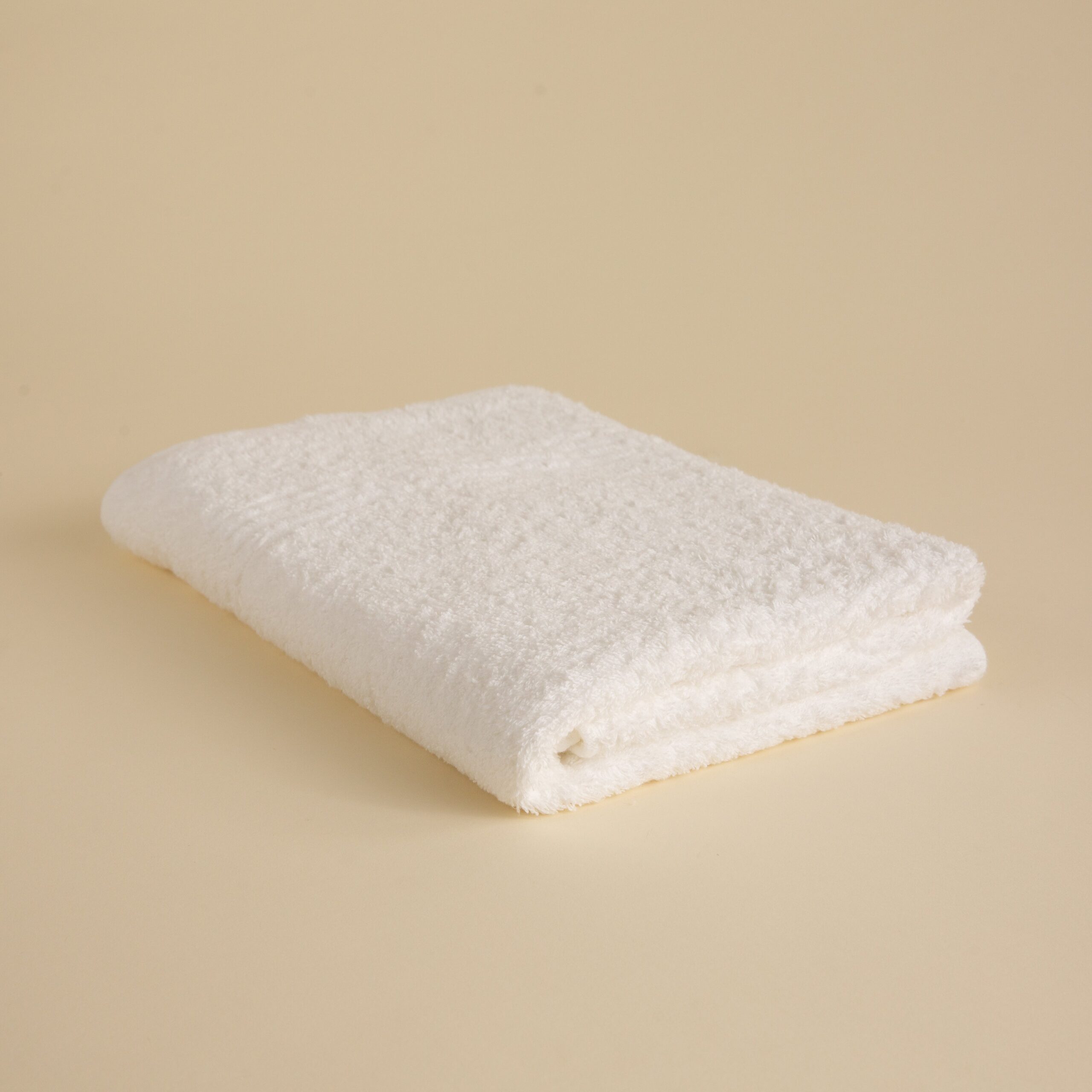 FineDetailsDay1-459 Stack of white towels in various sizes on a beige background