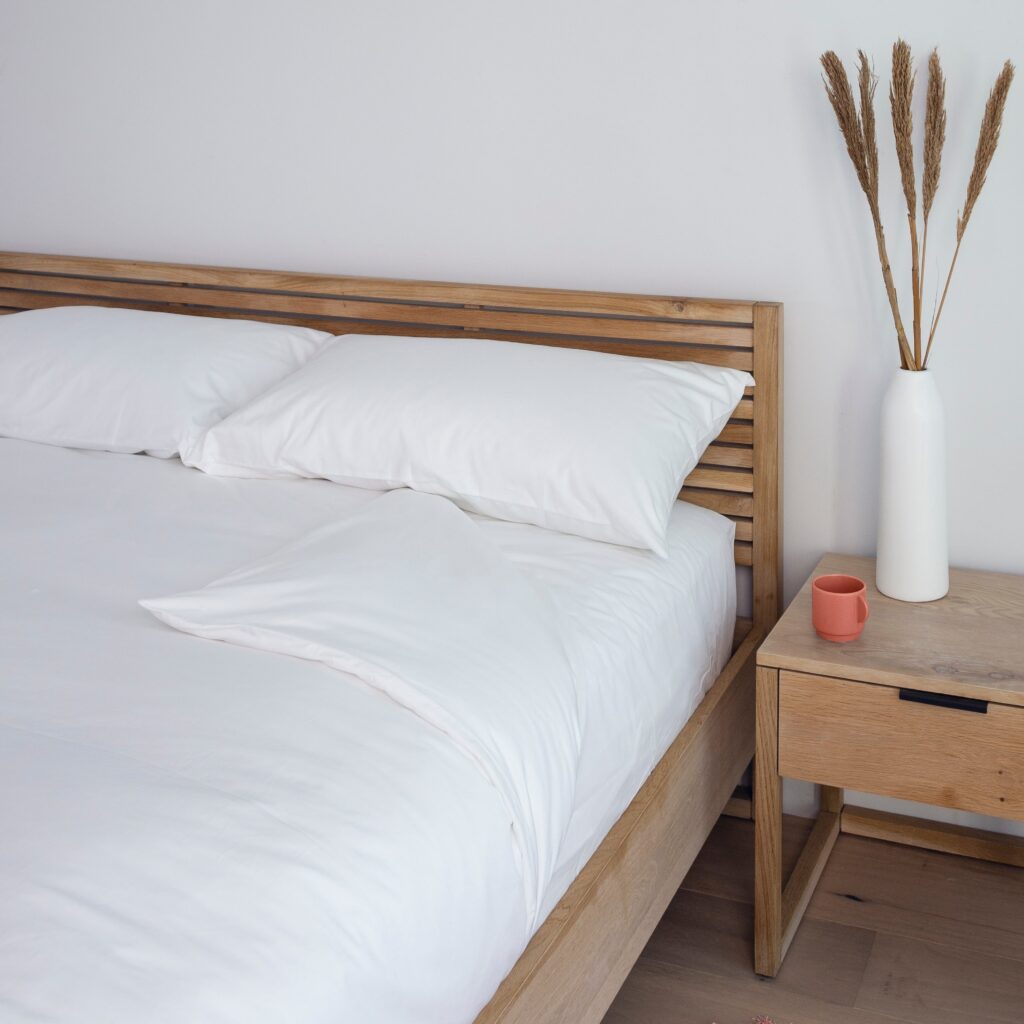 Bedroom with wooden bed and nightstand, white bedding, and decorative elements.
