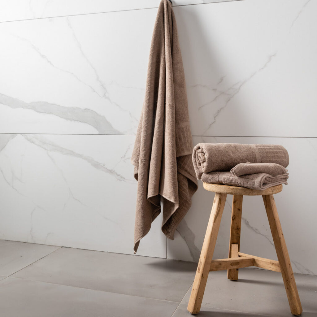 A stack of folded brown towels, with sizes varying from bottom to top, on a white background.