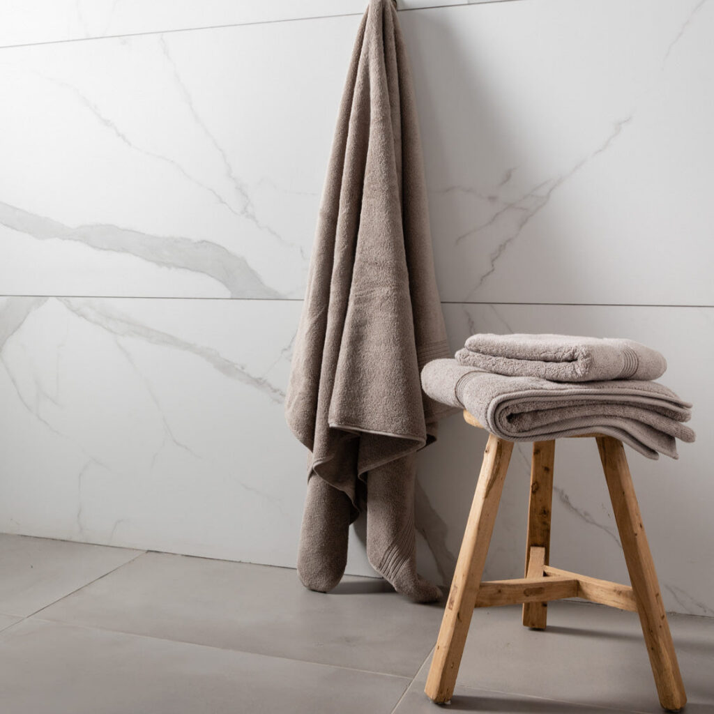 A set of folded towels in varying shades of gray and blue, placed on a wooden