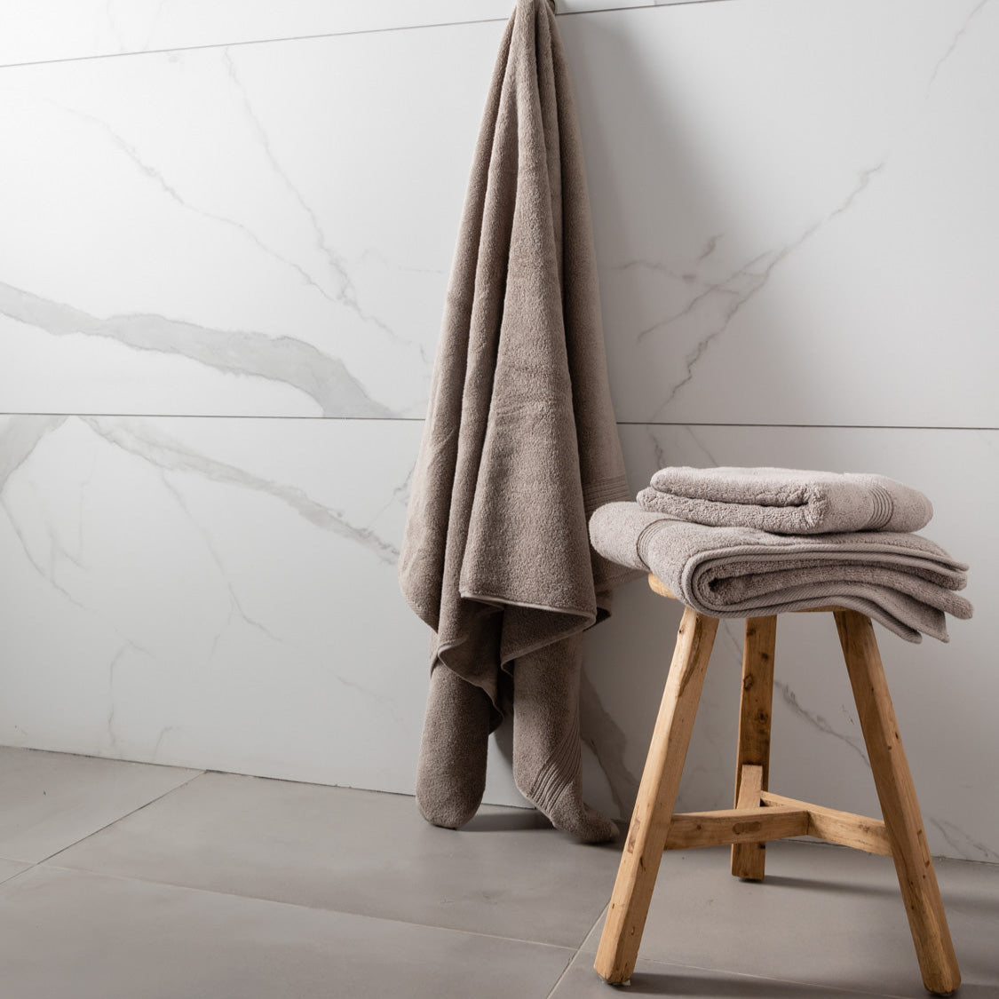 MG_9706 A set of folded towels in varying shades of gray and blue, placed on a wooden