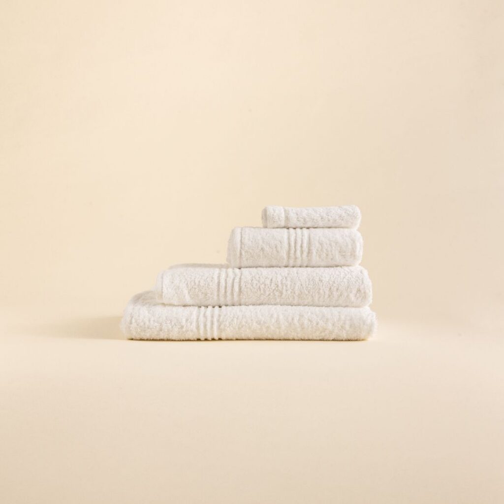 Stack of white towels in various sizes on a beige background