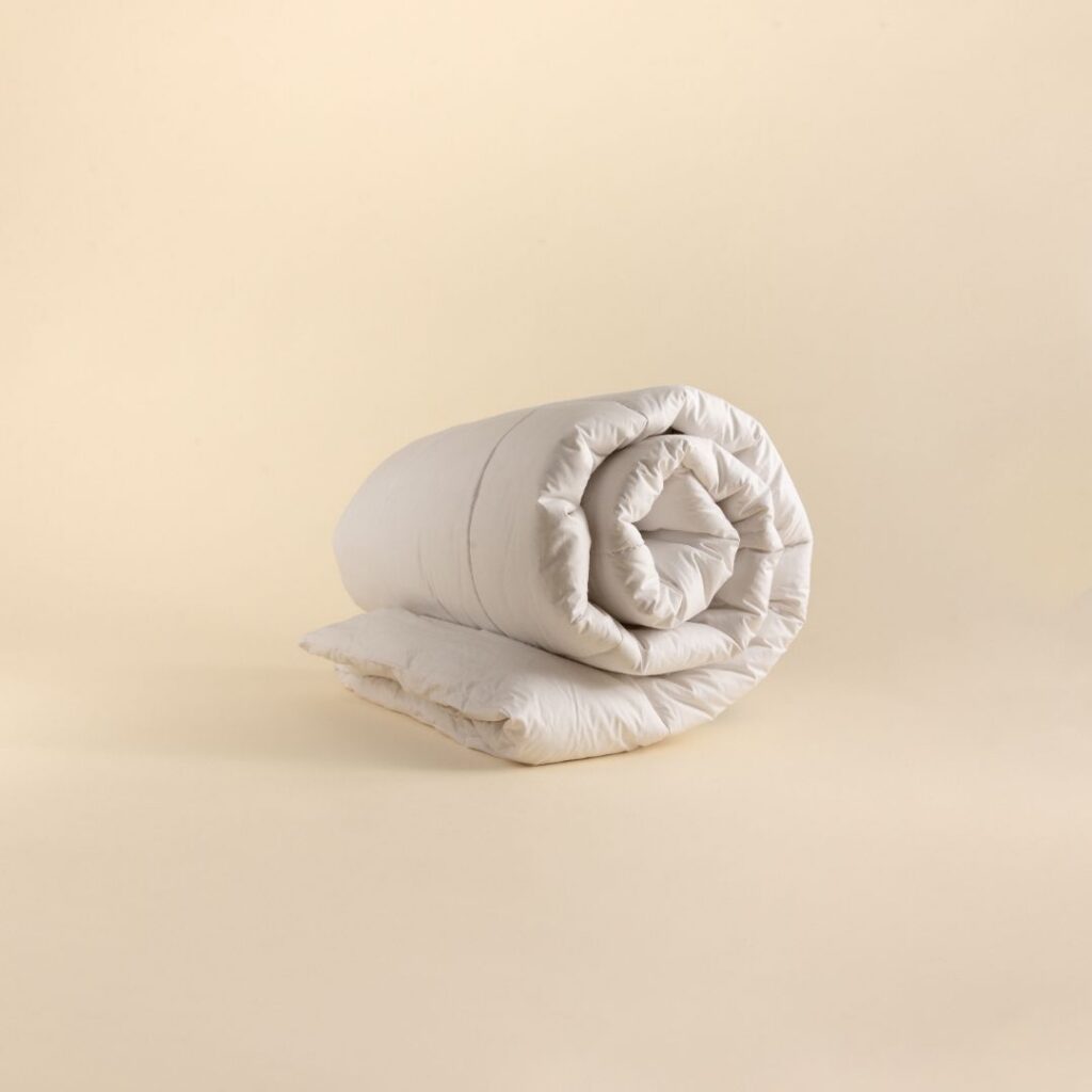 A rolled deluxe microfibre duvet inner on a plain background.