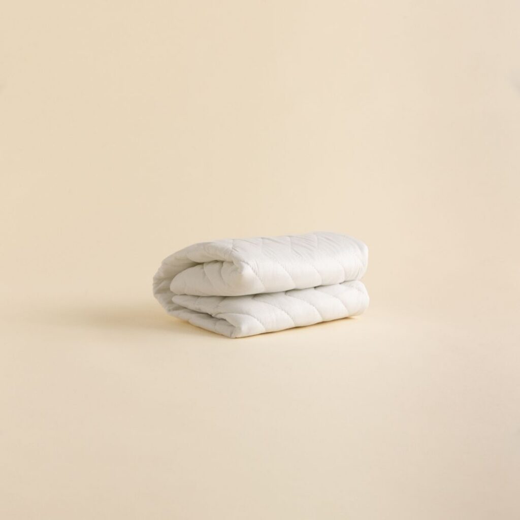 A folded white quilted pillow protector on a plain background.